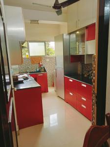 una cocina con armarios rojos y encimeras negras en happystay@casablanca2 en Chennai