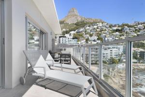 a balcony with white chairs and a view of a city at Seacliffe 502 by HostAgents in Cape Town