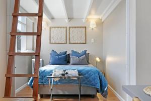 a bedroom with a blue bed and a ladder at Studio on Hope by HostAgents in Cape Town