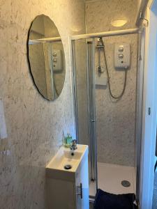 a bathroom with a shower and a sink and a mirror at Babbling Brook Guesthouse in Keswick