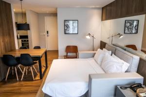 um quarto com uma cama branca e uma mesa em Estúdio novo com serviço de hotel em Florianópolis