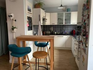 une cuisine avec une table en bois et deux chaises bleues dans l'établissement Appartement calme - Parking - Métro, à Ivry-sur-Seine