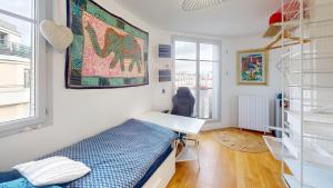Schlafzimmer mit einem Bett, einem Schreibtisch und einem Fenster in der Unterkunft Boho studio near the Eiffel Tower in Paris