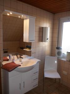 La salle de bains est pourvue d'un lavabo, d'un miroir et d'une chaise. dans l'établissement Ferienhaus Baarsen 30, à Bad Pyrmont