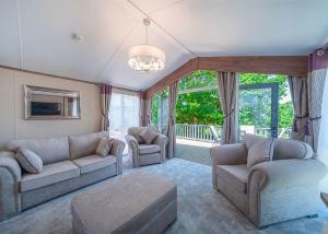 a living room with couches and chairs and a chandelier at Andrewshayes Orchard Retreat in Axminster