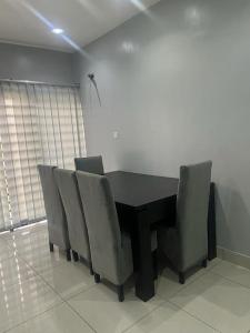 mesa de comedor con sillas y mesa negra en Luxe Living:4Bed, TV, Pool& WiFi, en Lekki