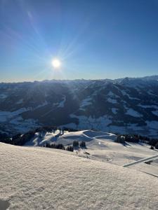 a view of a snowy mountain with the sun in the background at Appartement Wurzrainer in Westendorf +55 photos