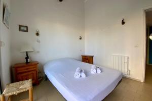 Un dormitorio con una cama blanca con toallas. en GROOMI La Carnonaise- Maison familiale en bord de mer ! en Mauguio