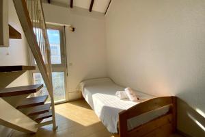 um pequeno quarto com uma cama e uma escada em GROOMI La Carnonaise- Maison familiale en bord de mer ! em Mauguio