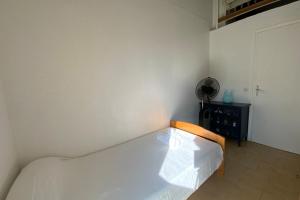 uma cama num quarto com uma parede branca em GROOMI La Carnonaise- Maison familiale en bord de mer ! em Mauguio