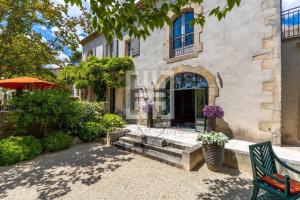 a building with a bench and an umbrella at Mas de L'Amarine in Saint-Rémy-de-Provence