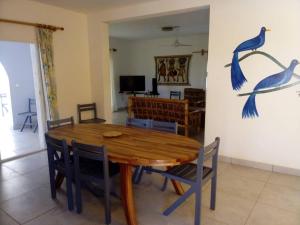 uma sala de jantar com uma mesa de madeira e pássaros azuis na parede em Les Filaos-Villa entre fleuve saloum et ocean em Palmarin