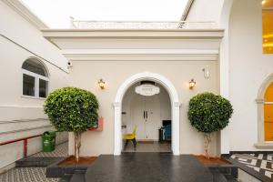 an entrance to a white building with two trees at CSR Landmark Resorts in Coimbatore +117 photos