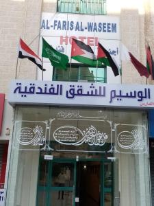 a group of flags flying in front of a building at الفارس الوسيم للشقق الفندقيه in Amman