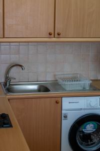 een keuken met een wastafel en een wasmachine bij Princess Residence in Ayios Dhometios