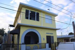 a yellow and white house with a car parked in front at 1BR Plus Basement, Near Beach and Restaurants in San Juan