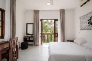 a white bedroom with a bed and a balcony at Villa Ceylanka in Talpe