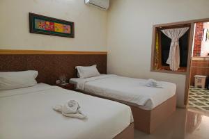 two beds in a room with towels on them at Adisa Homestay in Rampal