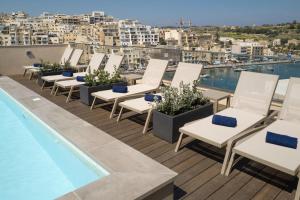 a row of lounge chairs and a swimming pool on a roof at Portside Lodge in Marsaskala
