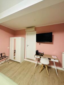 een kamer met een bureau en een tv aan de muur bij Casa flowers 1 in Ciampino