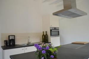 une cuisine avec un vase de fleurs violettes sur le comptoir dans l'établissement De Bossenaarshoeve, à Markedal