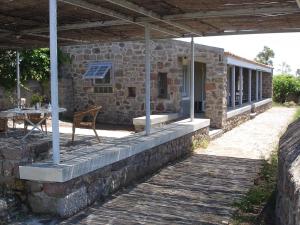 a stone house with a table and a chair on a patio at To Spitaki House in Perdika