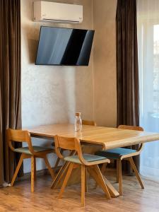 una mesa de madera y sillas con un televisor encima. en Deluxe Old Ungvar Apartments, en Uzhhorod