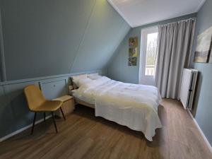 Natuurvilla De Heerlickheyt في Hoogersmilde: غرفة نوم بسرير وكرسي ونافذة