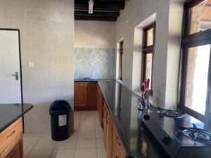 a large kitchen with a black counter top and windows at Lovely house on 4 hectares in John Galt Village - 2011 in Nyanga