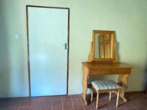 uma cómoda de madeira com um espelho e uma cadeira ao lado de uma porta em Lovely house on 4 hectares in John Galt Village - 2011 em Nyanga