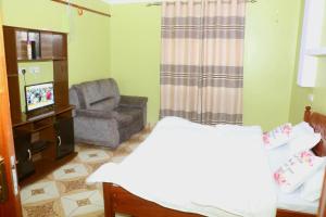 a room with a bed and a chair and a television at Lokorye Homes in Makutano