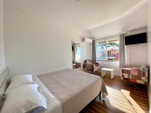 a bedroom with a bed and a large window at Pousada Areia Cristal in Bombinhas