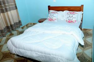 a bed with white sheets and pillows on it at Lokorye Homes in Makutano