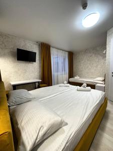 a bedroom with a large white bed and a television at Naciku SPA Hotel in Bukovel