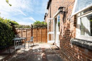 een patio met een tafel en stoelen naast een gebouw bij Central Village Cottage, The Corders in Moreton in Marsh