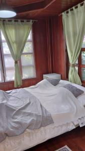 um quarto com uma cama branca e 2 janelas em Aran Cottage Ngamwongwan The Pool Villa in japanese Garden em Nonthaburi