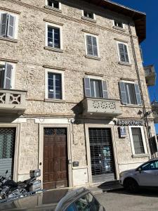 un edificio de piedra con una puerta y un coche aparcado delante en Appartamento Forte Malatesta en Ascoli Piceno