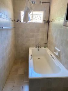 La salle de bains est pourvue d'une baignoire blanche et d'une fenêtre. dans l'établissement Cosy 3 bedroom cottage - 2034, à Kingsmead