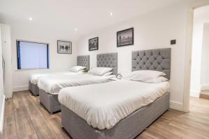 two beds in a room with white walls and wood floors at Camden Apartments 2 in Liverpool
