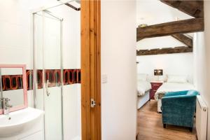 a bathroom with a sink and a bedroom at Poppy Cottage - Great Houndbeare Farm Holiday Cottages in Aylesbeare