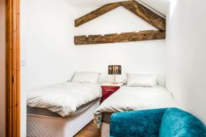 a bedroom with two beds and a mirror on the wall at Poppy Cottage - Great Houndbeare Farm Holiday Cottages in Aylesbeare