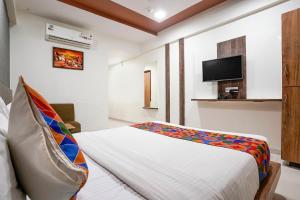 um quarto com uma cama e uma televisão na parede em FabHotel Galaxy I em Ahmedabad