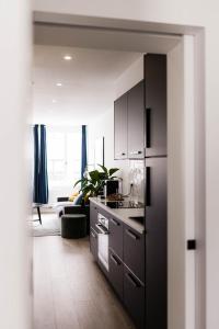 a kitchen with black cabinets and a living room at Gorgeous getaway in the old city centre of Antwerp in Antwerp