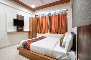 um quarto com uma cama e uma televisão em FabHotel Galaxy I em Ahmedabad
