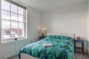 um quarto com uma cama com um cobertor azul e verde em Seaside Serenity: Stylish Sea View Apartments in Herne Bay em Kent