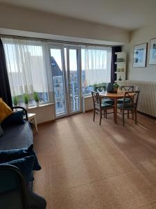 a living room with a table and chairs and windows at Studio Jules De Trooz in Blankenberge