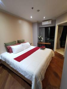 - une chambre avec un grand lit et une couverture rouge et blanche dans l'établissement Grand​ Diamond Suite Condominium, à Bangkok