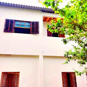 un edificio blanco con ventanas rojas y un árbol en Mazz_q_casa en Ilhabela