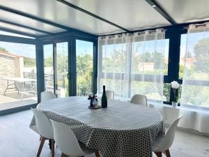 una sala da pranzo con tavolo, sedie e finestre di Le Cottage - Jolie Maison à Buxerolles a Buxerolles