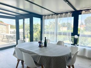 a dining room with a table and chairs and windows at Le Cottage - Jolie Maison à Buxerolles in Poitiers